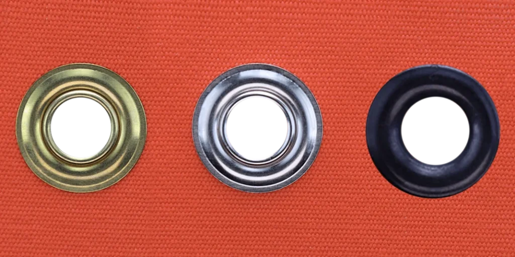 Brass, nickel plated and dull black grommets set in orange canvas showing finish options
