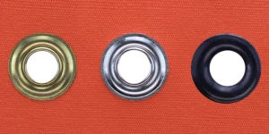 Brass, nickel plated and dull black grommets set in orange canvas showing finish options