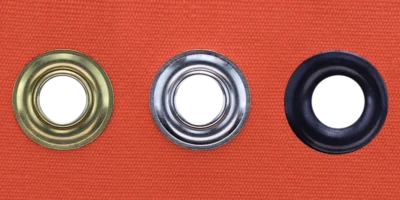 Brass, nickel plated and dull black grommets set in orange canvas showing finish options